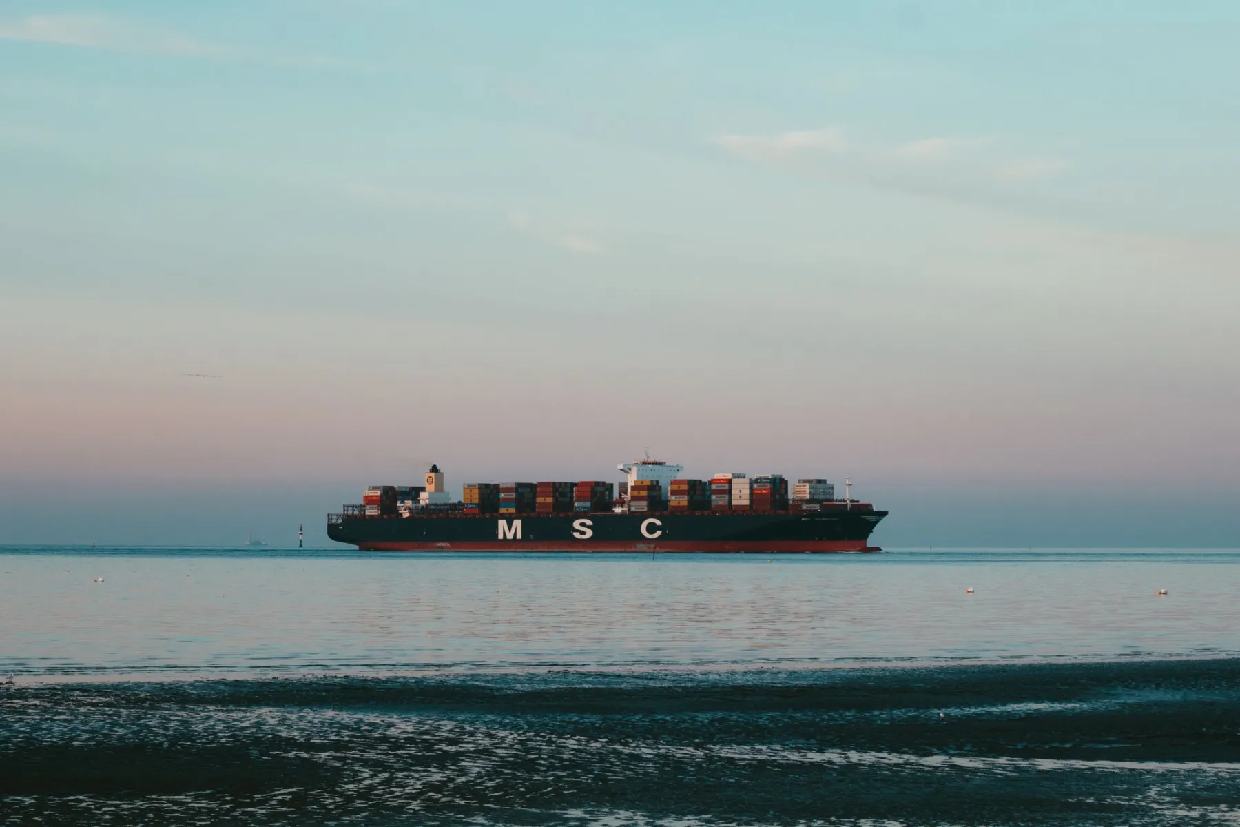 A bulk carrier on the Gulf horizon at dusk, last light on flat water